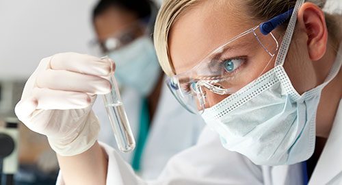 Scientist looking at a vial of heavy water for analytical research applications of deuterium oxide.