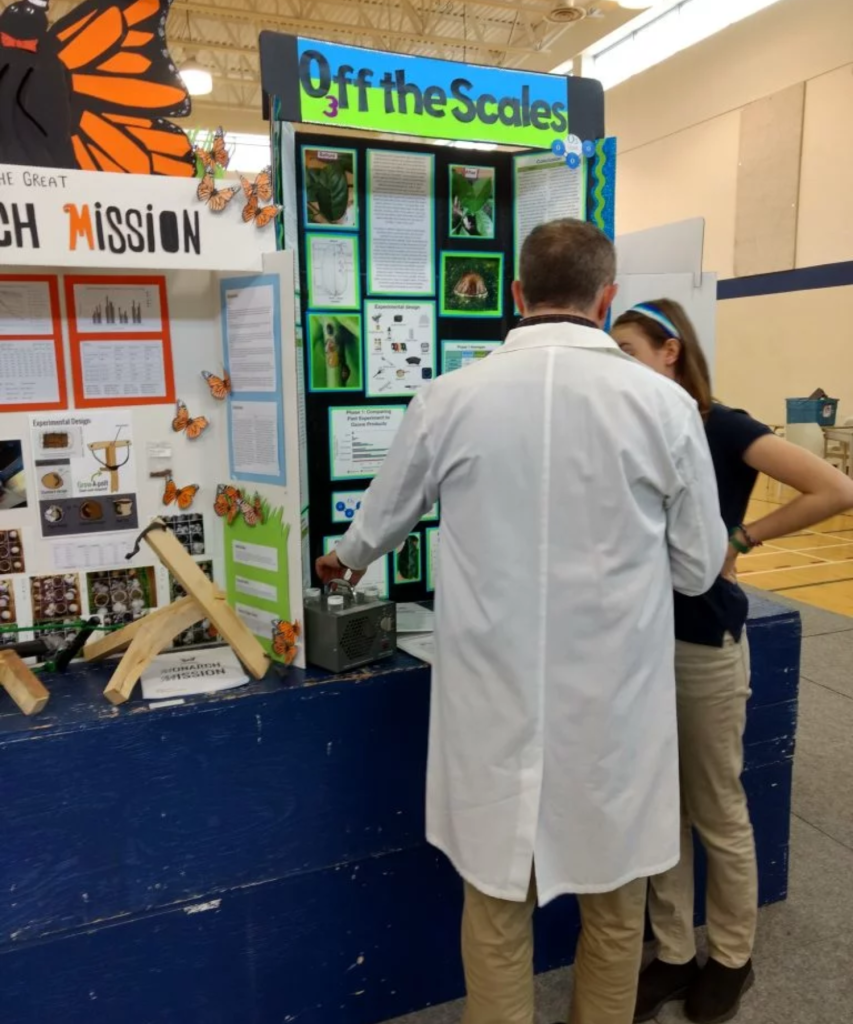 An Isowater employee interacting with a student at a school science fair.