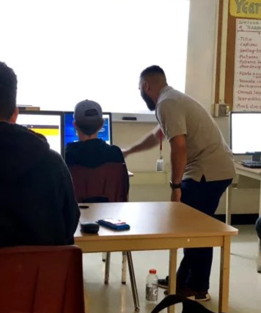 An Isowater employee pointing at a computer in a school classroom.